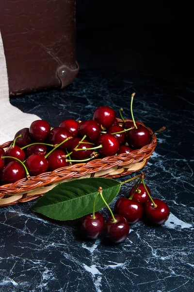 Várias cerejas vermelhas doces e grande folha verde na mesa. Fres — Fotografia de Stock