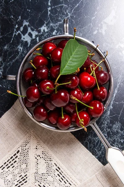 Fresh organic sweet cherry and big green leaf in steel colander — Stock Photo, Image