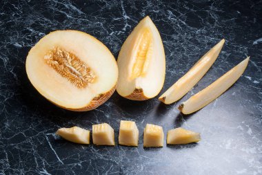 Yarım ve dilimlenmiş honeydew kavun meyve karanlık mermer arka plan üzerinde