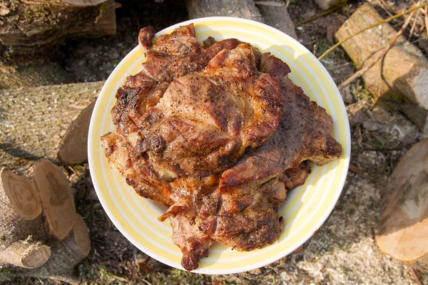 Juicy pork steaks cooked on an open flame grill on big white pla