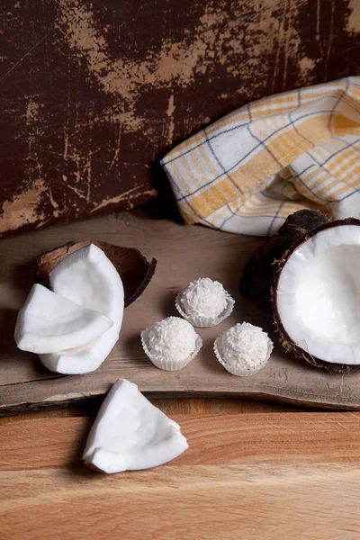 Coco con pulpa blanca y caramelos blancos sobre fondo de madera — Foto de Stock