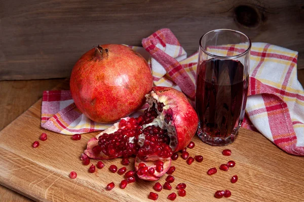 Grenade rouge fraîche et verre de jus de fruits frais sur un bois — Photo