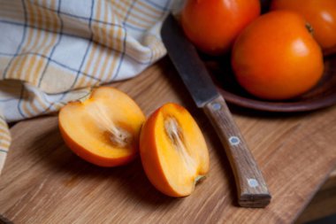 Tahta bir arka planda tam olgun hurma ve dilimlenmiş meyve.