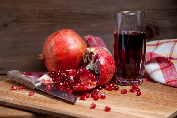Fresh red pomegranate with vintage knife and glass of fresh rudy