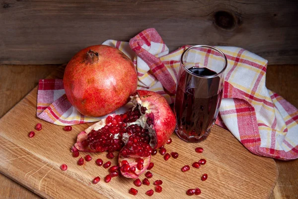 Grenade rouge fraîche et verre de jus de fruits frais sur un bois — Photo