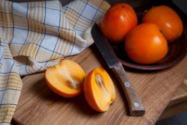 Tahta bir arka planda tam olgun hurma ve dilimlenmiş meyve.