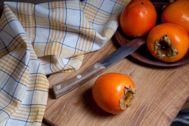 Lezzetli taze hurma meyveleri ve ahşap zemin üzerinde eski model bıçakla yenmeye hazır.