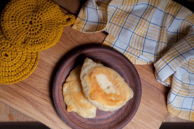 Ahşap masada iki ayrı kızarmış etli kil tabak. Tatar geleneksel turtaları.