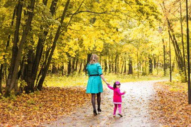 Anne ve kızı sonbahar Park'ta yürüyordunuz, arkadan görünüm
