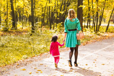 Anne ve kızı sonbahar Park'ta yürüyordunuz, arkadan görünüm