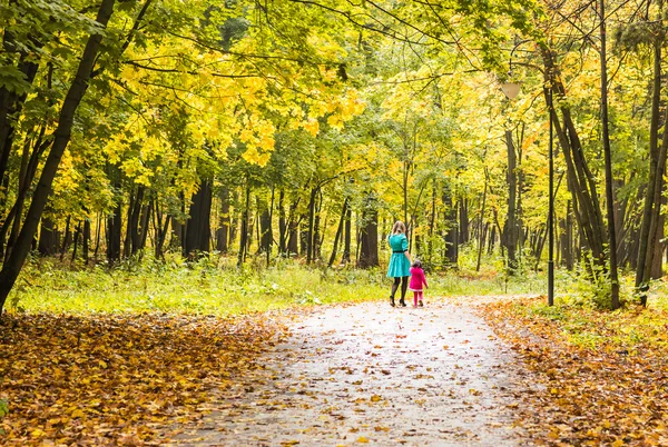 Moeder en dochter achteraanzicht wandelen in de herfst park, — Stockfoto