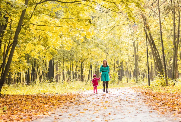 Anne ve kızı tutuşup Park'ta yürüyüş. Aile yaşam tarzı, sonbahar sezon kavramı — Stok fotoğraf