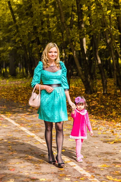 Mother and daughter walking holding hands at park. Family lifestyle, autumn season concept
