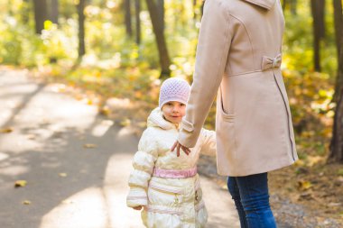 Anne ve kızı birlikte sonbahar parkta oynarken