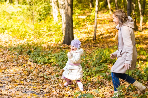 Mãe e filha brincando juntas no parque de outono — Fotografia de Stock