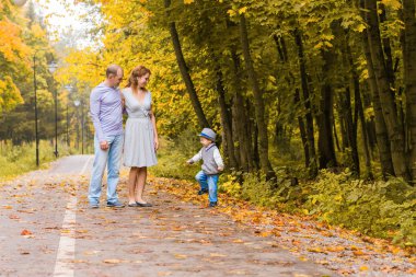 Genç aile bir sonbahar günü parkta yürüyüş