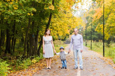Genç aile bir sonbahar günü parkta yürüyüş