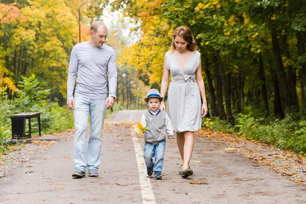 Junge Familie geht an einem Herbsttag im Park spazieren — Stockfoto