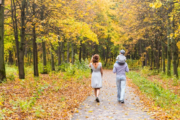 Ung familj promenader i parken en höstdag — Stockfoto