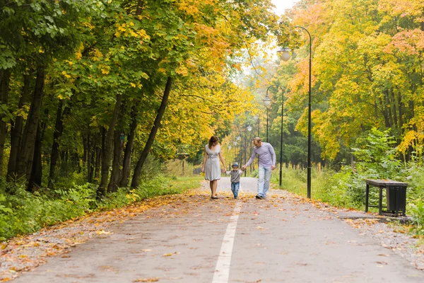 Junge Familie geht an einem Herbsttag im Park spazieren — Stockfoto