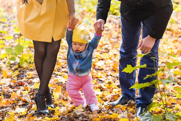 Niña pequeña cogida de la mano con su madre y su padre afuera en un día de otoño — Foto de Stock