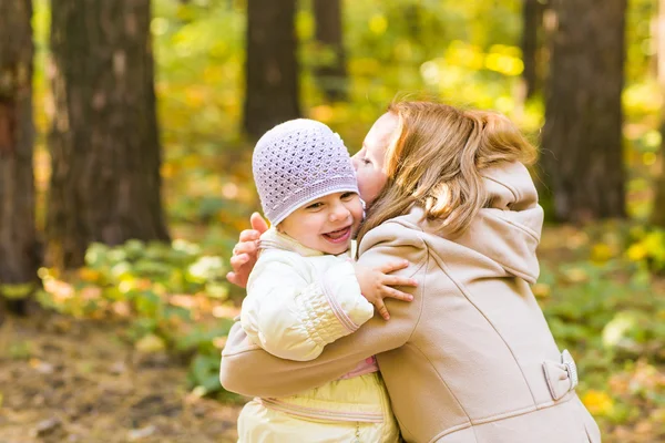 Маленькая девочка и ее мать играют в осеннем парке — стоковое фото