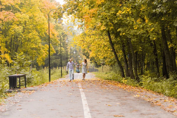 Lopend onderaan de weg buiten in de groene natuur en gelukkige jonge familie. — Stockfoto