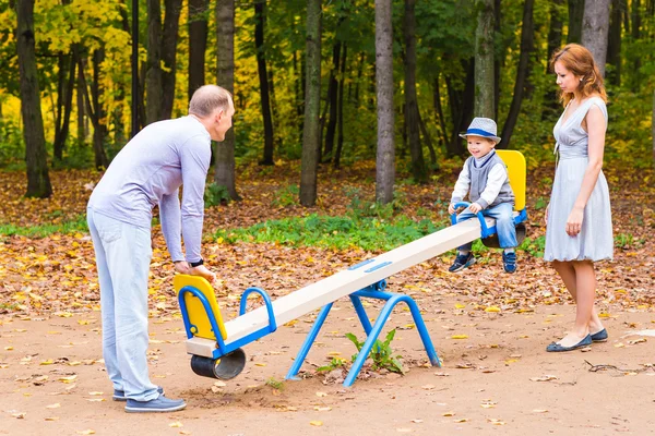 Niño juguetón con los padres en el patio al aire libre. Mamá, papá y bebé — Foto de Stock