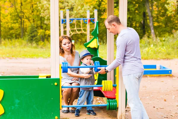 Niño juguetón con los padres en el patio al aire libre. Mamá, papá y bebé — Foto de Stock