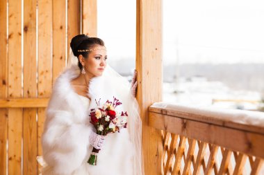 Genç gelin kış zamanında çiçek buketi ile