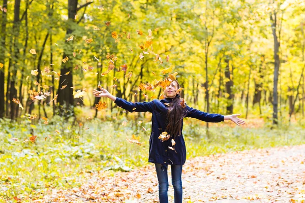 Portret van een tiener meisje speelt met herfstbladeren in bos — Stockfoto