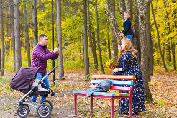 Семья, детство, время года, технология и концепция людей - счастливая семейная фотография в осеннем парке — стоковое фото