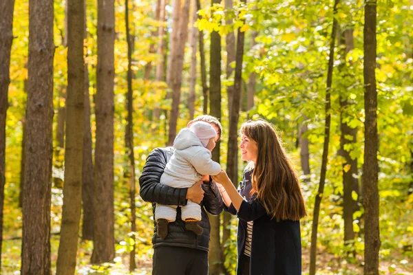 秋の公園で生まれたばかりの赤ちゃんを持つ夫婦を笑顔 - 愛、親、家族、季節、人の概念 — ストック写真