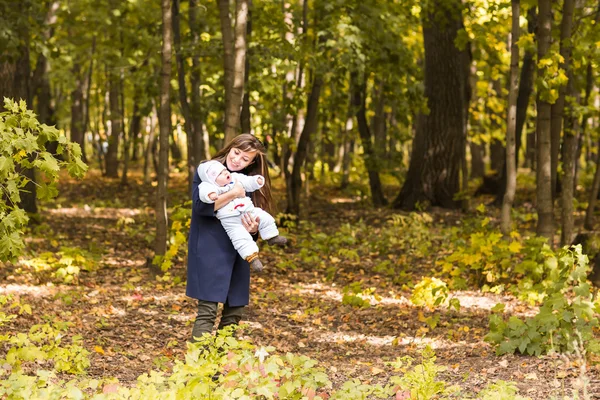 Glückliche Familie, Mutterschaft und Babykonzept. Lächelnde Mutter und kleine Tochter beim gemeinsamen Spielen in einem Park. — Stockfoto