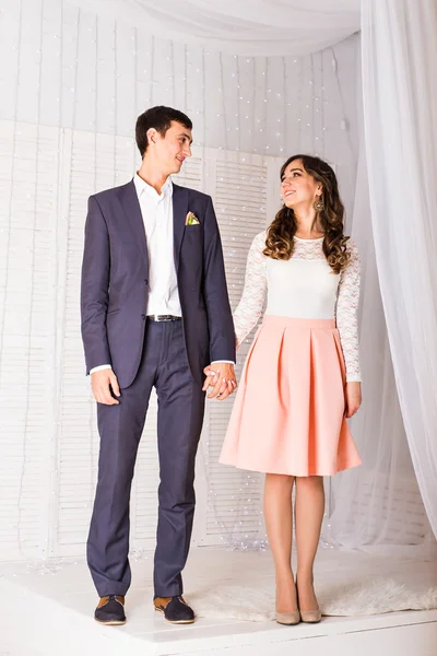 Glückliches stilvolles Paar hält Händchen vor dem Hintergrund des Interieurs. — Stockfoto