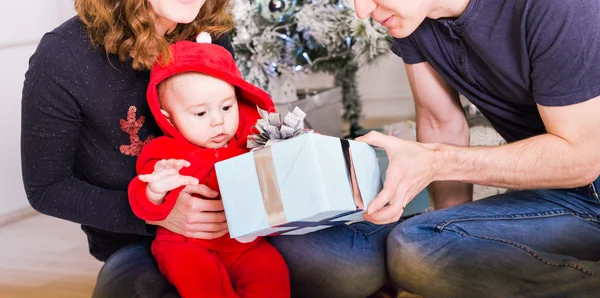 Szczęśliwa rodzina trzyma prezenty świąteczne w pobliżu drzewa Xmas. Dziecka, matki i ojca, zabawy w domu — Zdjęcie stockowe
