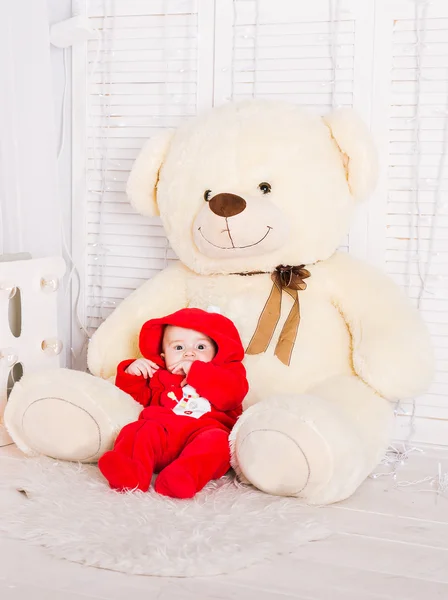 Cute baby with big teddy bear on white room