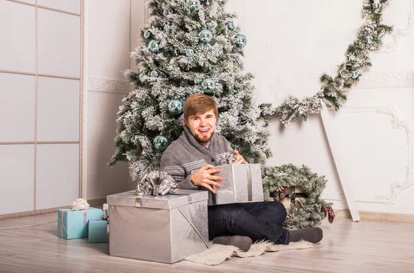 Mutlu adam evde Noel ağacı yakınındaki bir hediye açılış — Stok fotoğraf