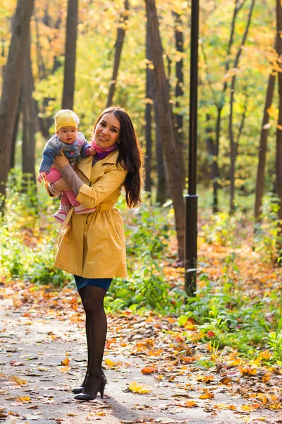 幸せな家族の母親と赤ちゃんは自然の秋に葉で笑う — ストック写真