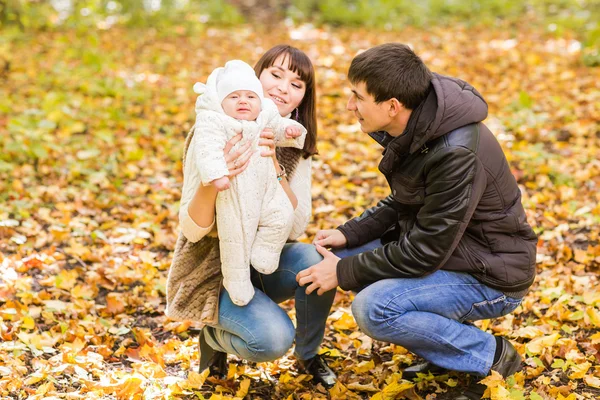 Šťastný a mladá rodina relaxační společně v zlatých a barevné podzimní přírody. — Stock fotografie