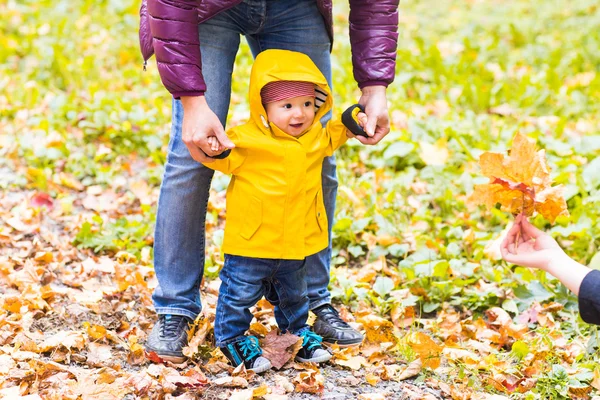 Padre e Hijo caminando. Bebé dando los primeros pasos con la ayuda del padre en el jardín de otoño en la ciudad — Foto de Stock