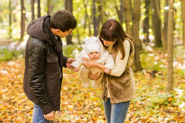 Familia joven con su bebé recién nacido que pasa tiempo al aire libre en el parque de otoño . — Foto de Stock