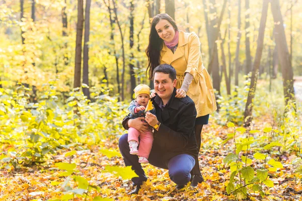 Familia joven y feliz con su hija pasando tiempo al aire libre en el parque de otoño . —  Fotos de Stock