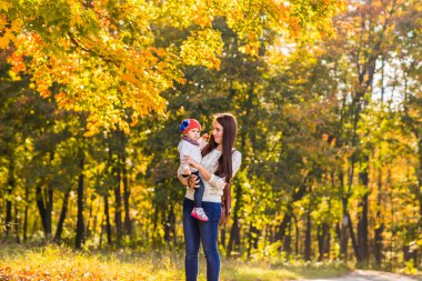 Güzel anne ve küçük kızı birlikte sonbahar Park'ta yürüyordunuz