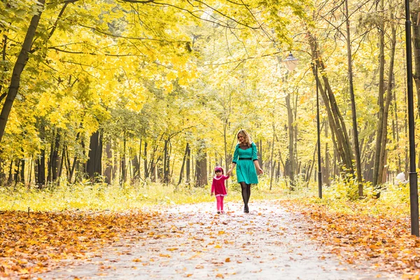 Mãe feliz e filha criança de mãos dadas no dia de verão ou outono . — Fotografia de Stock