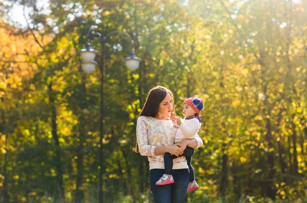 Güzel anne ve küçük kızı birlikte sonbahar Park'ta yürüyordunuz