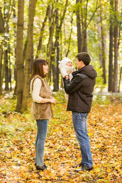 Retrato de feliz pareja joven con bebé hijo en el parque de otoño — Foto de Stock