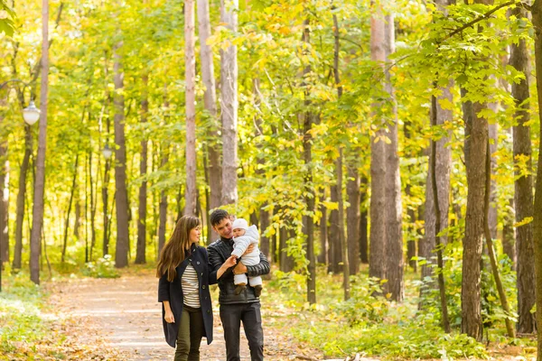Gelukkige jonge familie wandelen op de weg buiten in de natuur van de herfst. — Stockfoto