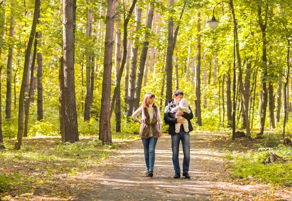 Jovem família feliz andando pela estrada fora no outono natureza . — Fotografia de Stock