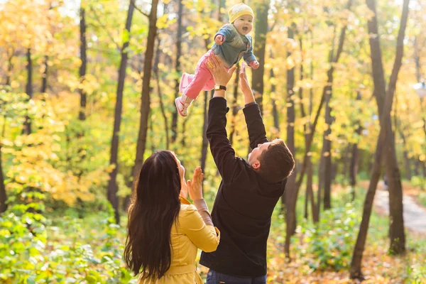 Kärlek, föräldraskap, familjen, säsong och människor koncept - leende par med baby i höst park — Stockfoto